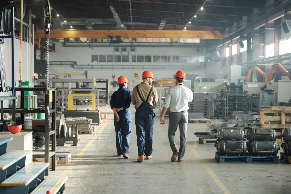 Back view of three young contemporary workers of industrial plant walking along